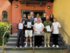 Gemeinsam mit der stellvertretenden Bürgermeisterin Silvia Godde (Mitte hinten) sowie Christine Fester (2. v. l. hinten) und Vanessa Drosten (rechts hinten) von der VHS freuen sich (v. l. n. r.) Helena Sichtermann, Mahdi El Sayed, Neo Davis Wolny, Michaela Stratmann, Robbie Thomas Korth, Tobias Bialluch und Slawomir Juszczyk.